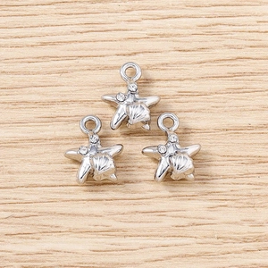 Macro shot of three silver starfish pendants with rhinestones on a wooden background