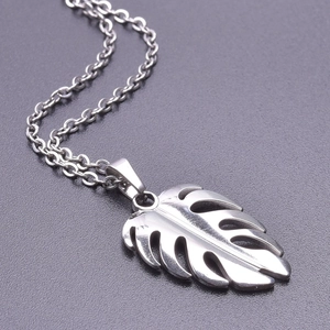 Macro shot of silver tropical monstera leaf pendant necklace in hollowed design
