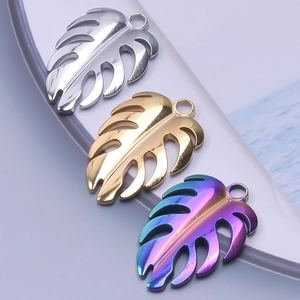 Macro detail of leaf-shaped monstera pendants in silver, gold, and rainbow finish