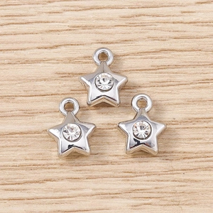 Three silver star pendants with sparkling rhinestones on light wood background