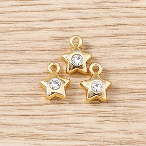 Macro shot of three star-shaped gold pendants with clear rhinestones on wood