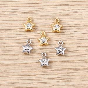 Close-up of gold and silver star charms with rhinestones on light wood background