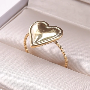 Macro view of gold heart ring with textured woven band in a premium jewelry box