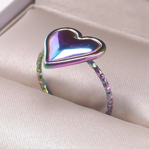 Macro detail of iridescent heart ring with textured band in a beige satin jewelry box