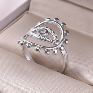 Detailed close-up of retro stainless steel evil eye ring on a beige textured jewelry box
