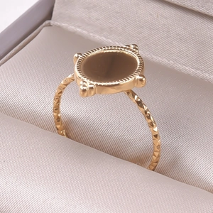 Macro detail of a golden adjustable ring with diamond-cut texture and disc-shaped top surface