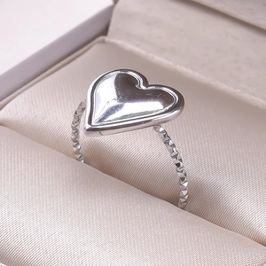 Close-up of silver heart ring with textured band displayed in a beige jewelry box