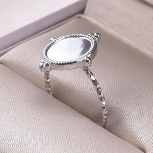 Detailed close-up of a silver stainless steel oval ring with ornate engraved pattern