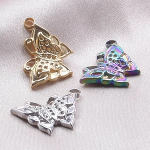 Vue détaillée des pendentifs papillons en or, argent et arc-en-ciel sur tissu en soie
