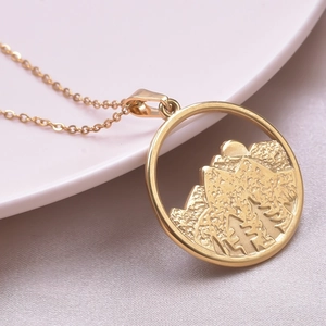 Macro de pendentif montagne doré avec détails de relief de forêt et soleil levant