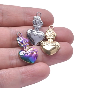 Trois pendentifs cœur épine en or, argent et arc-en-ciel tenus dans la main