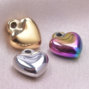 Macro shot of heart-shaped stainless steel charms in gold, silver, and gradient colors