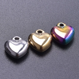 Macro shot of heart-shaped pendants in silver, gold, and rainbow finishes on dark fabric