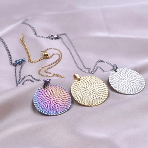 Three colors of round textured stainless steel pendant necklaces on purple satin fabric