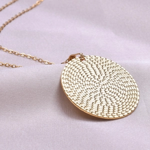 Detail of 18k gold plated round pendant with spiral woven texture and link chain
