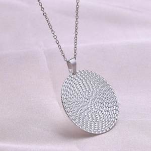 Detailed macro view of silver stainless steel circular pendant with woven texture design