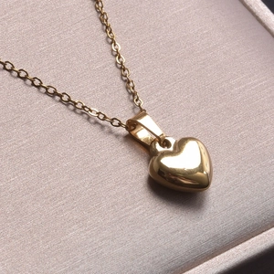 Detailed view of polished 18k gold plated stainless steel heart pendant on fine chain