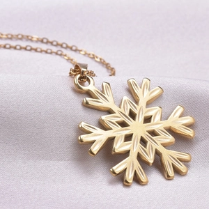 Detailed close-up of a 18k gold plated snowflake pendant with delicate radial engravings