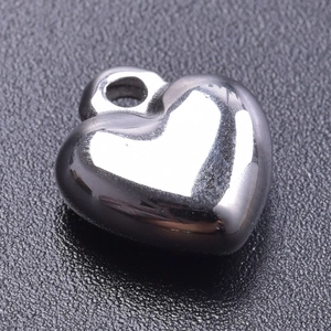 Close-up of polished silver heart pendant for DIY jewelry on a dark textured surface