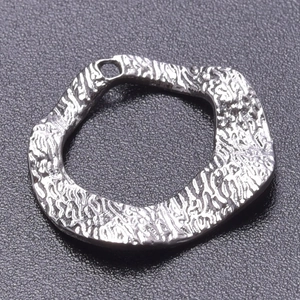Macro shot of silver stainless steel pendant featuring irregular lava texture and hanging hole
