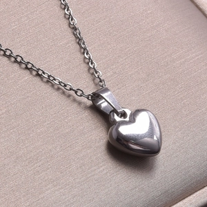 Macro shot of a polished heart pendant necklace on champagne silk jewelry gift box