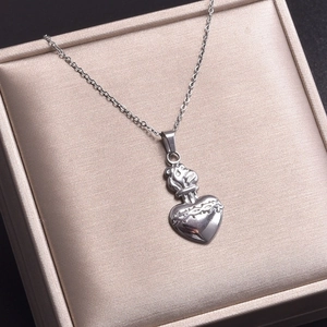 Détail d'un pendentif cœur sacré argenté avec motifs d'épines dans un écrin