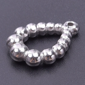 Macro detail of a silver teardrop beaded pendant with smooth polished metal spheres
