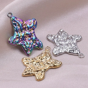 Detailed view of three 18k gold plated star pendants with hammer texture on pink satin