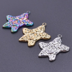 Macro detail of three star-shaped metal pendants with hammered texture and closed loop hangers