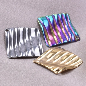 Vue macro de pendentifs carrés à texture froissée en finitions argent, or et irisé