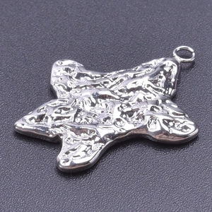Detail shot of the 18k silver star pendant with unique lava fold texture and metal grain