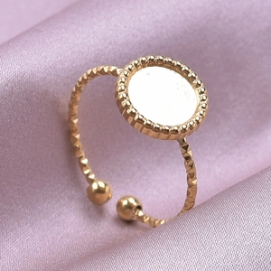 Detalle macro de base de anillo ajustable bañada en oro con textura sobre seda rosa