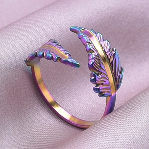 Dettaglio macro dell'anello a piuma iridescente su raso rosa con vivaci colori metallici