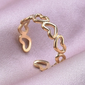 Detail van de gouden hartvormige opengewerkte ring op elegante paarse zijden stof