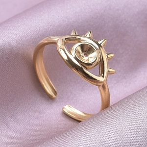 Dettaglio dell'anello occhio del male dorato con punte su seta viola di lusso