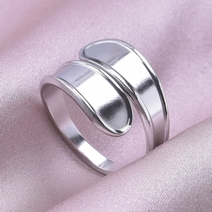 Close-up of a minimalist silver stainless steel adjustable ring on silk fabric