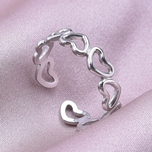 Detail van zilveren verstelbare ring met holle hartpatronen op roze zijden stof