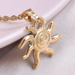 Macro view of a 18k gold-plated sun pendant necklace with detailed spiral patterns
