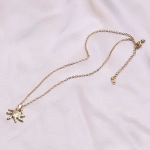 Macro detail of a 18k gold plated sun pendant necklace on elegant pink silk fabric
