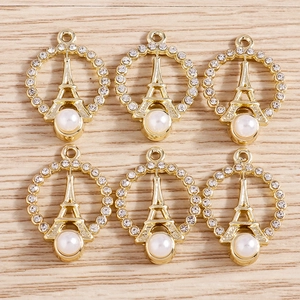 Macro shot of 6 gold Eiffel Tower charms with rhinestones and white pearls for DIY jewelry