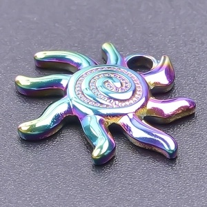 Macro shot of sun-shaped pendant with rainbow metallic gradient and spiral pattern