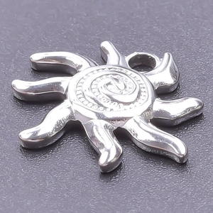 Polished silver sun pendant with spiral center and flame rays on grey background