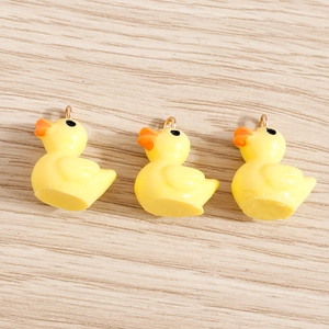 Detailed view of yellow resin duck charms with orange beaks and metal hanging loops