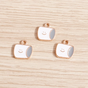 Détail de trois breloques souriantes en émail avec cadres en métal or rose sur bois