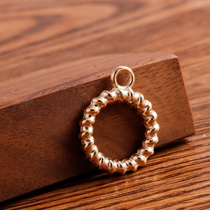 Detailed view of a gold-toned twist texture round pendant on a dark walnut display