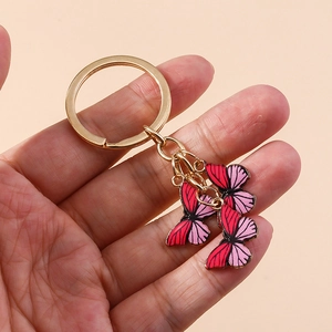 Vue détaillée de trois pendentifs papillons rose et rouge sur un anneau doré de porte-clés