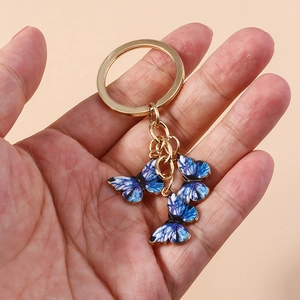 Détail de breloques papillon dégradé bleu et violet sur un porte-clés doré chic