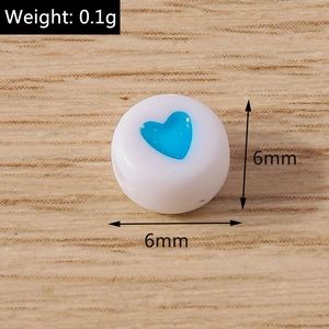 Dettaglio di una perla in acrilico bianco da 6mm con cuore blu su legno