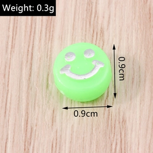 Dettaglio perla acrilica verde neon da 0,9cm con faccina sorridente argento e peso di 0,3g
