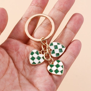 Fashionable green checkerboard heart keychain charms with gold ring held in hand